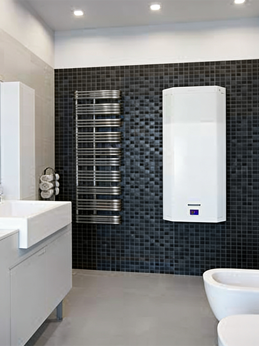 Bagno moderno con rivestimento a mosaico nero su cui è installato uno scaldacqua a pompa di calore bianco dal design compatto, posizionato accanto a uno scaldasalviette in acciaio.
